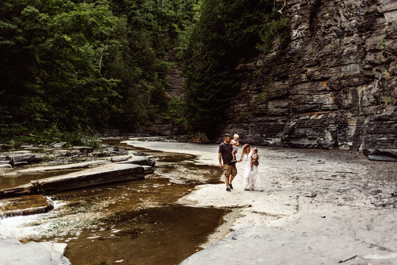 Family Photography, mom and dad walking beside water holding their children